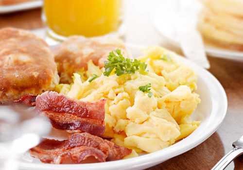 sunny breakfast shot close up, with scrambled eggs, bacon, and biscuits.