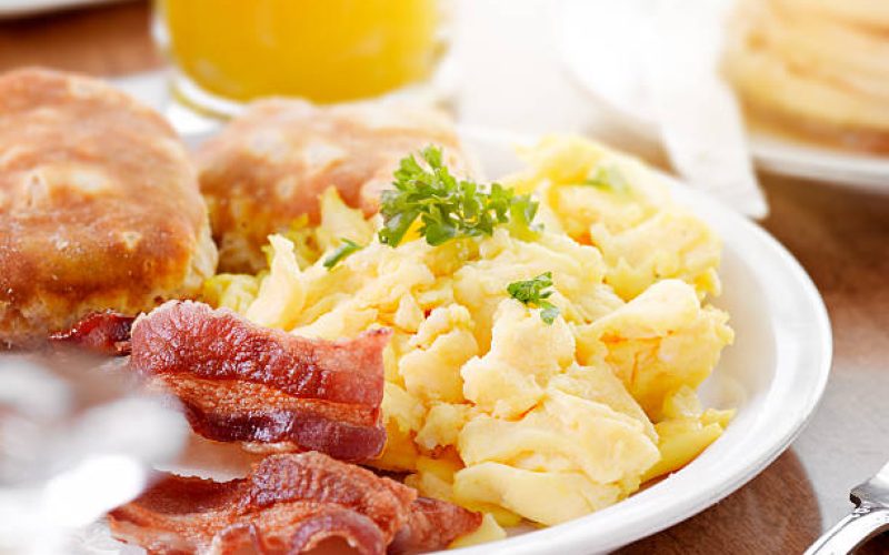 sunny breakfast shot close up, with scrambled eggs, bacon, and biscuits.